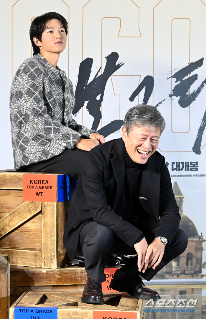 Why did Song Joong-ki go up to the box leaving the photo wall intact? 